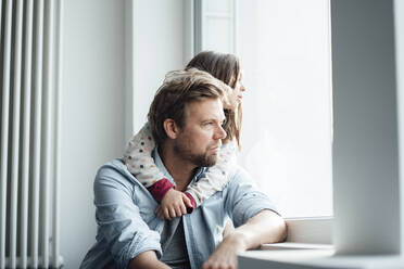 Mädchen mit Arm um den Vater, der durch das Fenster seines Hauses schaut - JOSEF04146