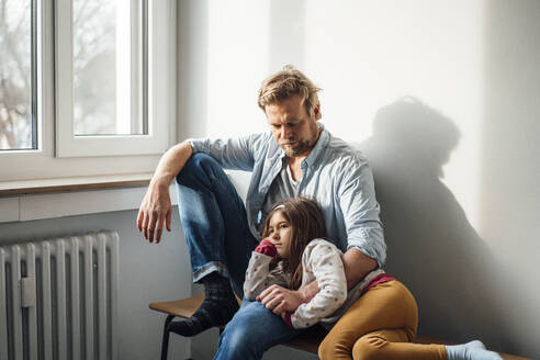 Girl resting on father's lap sitting at home - JOSEF04148