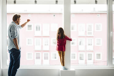Daughter and father standing by window at home - JOSEF04149