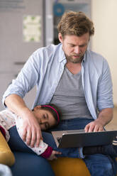 Businessman taking care of girl while using laptop at home - JOSEF04159