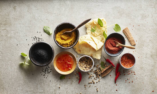 Studioaufnahme von Naan-Brot, Chili-Dip-Sauce und Schalen mit verschiedenen Masala-Gewürzen - KSWF02216