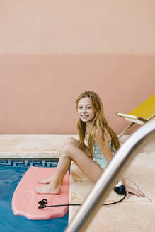 Smiling girl sitting at poolside - AGGF00093