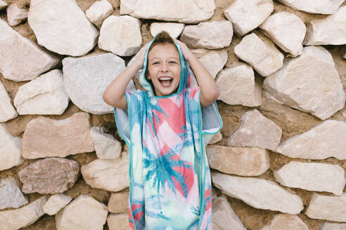 Happy girl in bathrobe standing in front of wall - AGGF00096