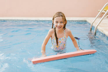 Lächelndes Mädchen mit Schwimmflügel im Pool - AGGF00098