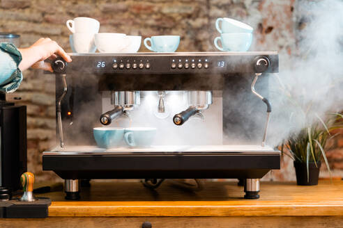 Crop gesichtslosen Barista Vorbereitung Kaffee in Kaffeemaschine auf dem Tresen in Café im Loft-Stil platziert - ADSF23009