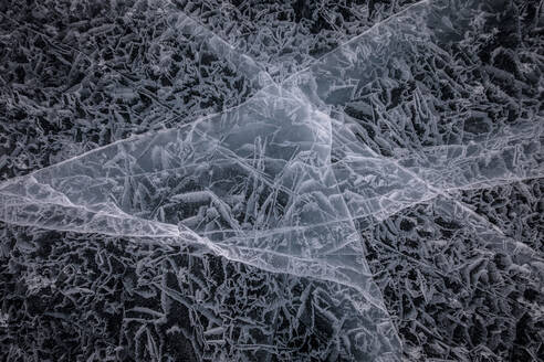 From above of frozen Lake Baikal surface with chaotic pattern and cracks as abstract background - ADSF23043