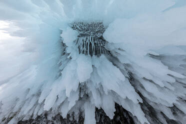 Riesige Eiszapfen, die im Winter von einer Felsenhöhle in der Nähe des Baikalsees hängen, als abstrakter Hintergrund von unten - ADSF23047
