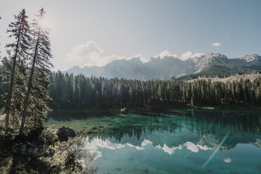 Karersee zwischen Bäumen an einem sonnigen Tag in Südtirol, Italien - MJRF00390