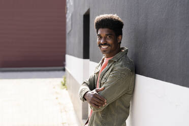 Smiling man with moustache leaning on wall outdoors - AFVF08620