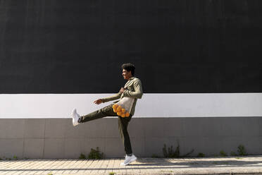 Happy man with bag of oranges kicking on footpath - AFVF08624