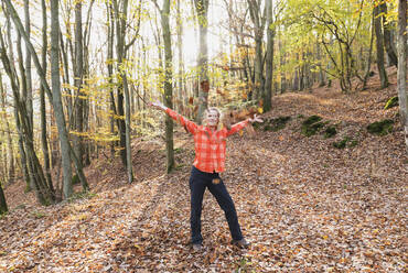 Portrait of adult woman playing with leaves in autumn forest - GWF06982