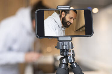 Man filming through smart phone at home - JCCMF01937