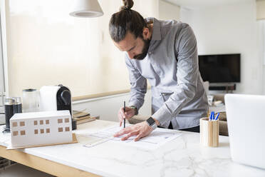 Male architect designing construction plan while working at home - JCCMF01945