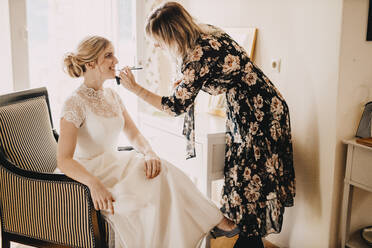 Maskenbildnerin trägt bei der Hochzeit Lippenstift auf die aufgeregte Braut auf - DAWF01893