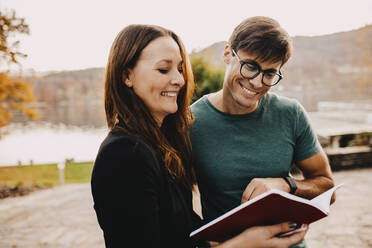 Smiling planner showing book to handsome customer - DAWF01918