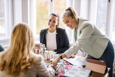 Lächelnde weibliche Fachkräfte im Gespräch mit einem Kunden im Büro - DAWF01921