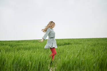 Unbekümmerte blonde Frau tanzt auf der Wiese - KIJF03741