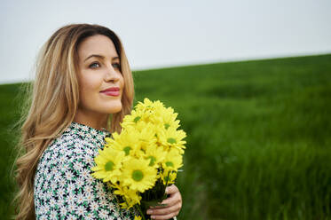 Beautiful woman looking away holding yellow flowers - KIJF03766