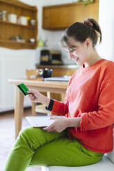 Woman with credit card doing home shopping through digital tablet at home - MCVF00776