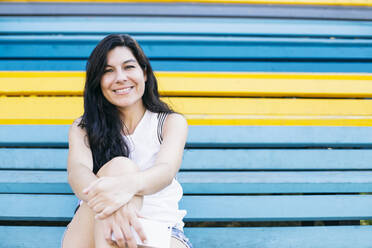 Beautiful woman sitting on multi colored steps - ABZF03552