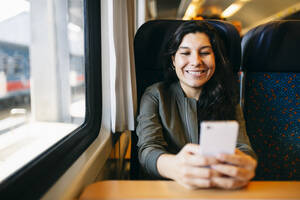 Mittlere erwachsene Frau benutzt Mobiltelefon im Zug - ABZF03567