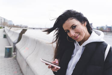 Lächelnde Frau, die ihr Handy in der Hand hält - SPCF01348