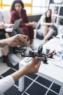 Männliche Ingenieure erläutern das Drohnenmodell mit Kollegen im Büro - SNF01232