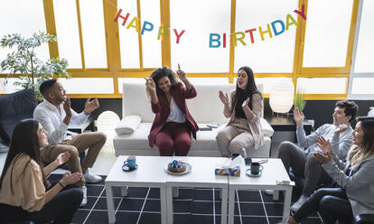 Male and female professionals clapping during birthday celebration at coworking office - SNF01238
