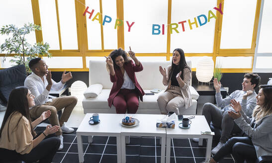 Männliche und weibliche Fachkräfte klatschen bei der Geburtstagsfeier im Coworking-Büro - SNF01238