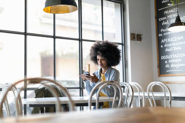 Eine Unternehmerin benutzt ihr Smartphone, während sie in einem Cafe sitzt - EIF00821