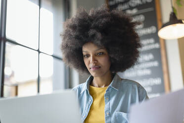 Afro-Geschäftsfrau mit Blick auf den Laptop im Cafe - EIF00830