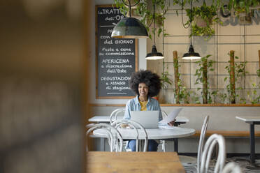 Lächelnde Geschäftsfrau mit Dokument im Café sitzend - EIF00832