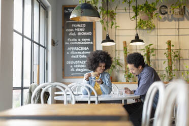 Businesswoman with coffee cup sitting with male client at cafe - EIF00843