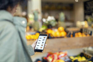 Frau kauft Lebensmittel über eine mobile Anwendung im Supermarkt - EIF00854