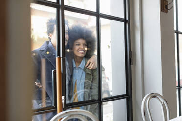 Man with girlfriend looking inside cafe through glass window - EIF00859