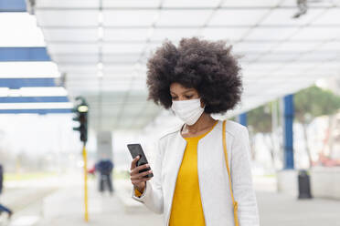 Afro-Geschäftsfrau benutzt Smartphone am Bahnhof während der Pandemie - EIF00861