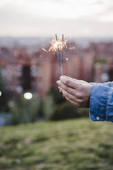 Mid adult woman holding sparklers during sunset - EBBF03401