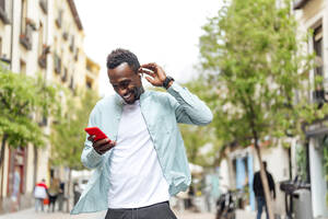 Young man in casual clothing using smart phone at street - PGF00535