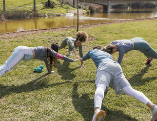 Männliche und weibliche Freunde trainieren in einem öffentlichen Park an einem sonnigen Tag - JRVF00466
