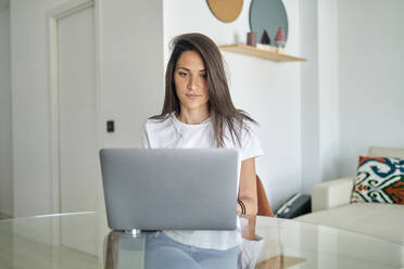 Mid adult woman using laptop at home - KIJF03779