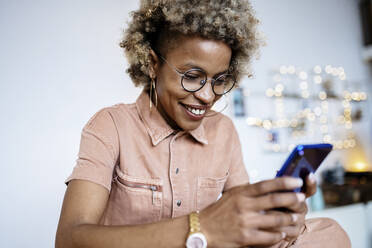 Unternehmerin mit Brille, die im Büro zu Hause ein Smartphone benutzt - RFTF00068