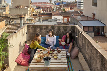 Female friends eating food on rooftop - VEGF04252