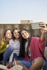 Glückliche Freundinnen nehmen Selfie durch Handy auf dem Dach - VEGF04260
