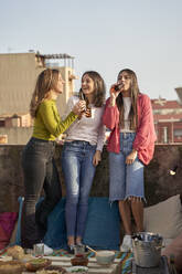 Cheerful female friends drinking beer on rooftop - VEGF04268