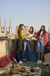 Happy female friends with beer bottle on rooftop - VEGF04276