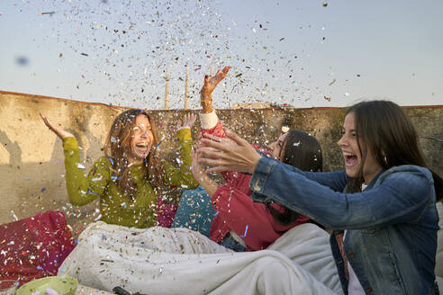 Happy woman blowing confetti while celebrating - VEGF04286