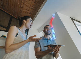 Physiotherapist and surprised female patient looking at holographic anatomical model of the spine - LIFIF00022