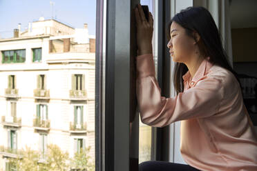 Young businesswoman looking through window of hotel - VEGF04324