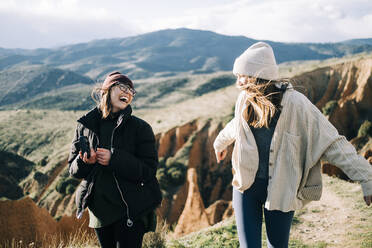 Young happy female travelers with photo camera having fun against mount on sunny day in back lit - ADSF23114