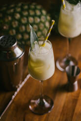 From above composition of sweet classic Pina Colada cocktails served on bar counter near shaker and jigger - ADSF23136